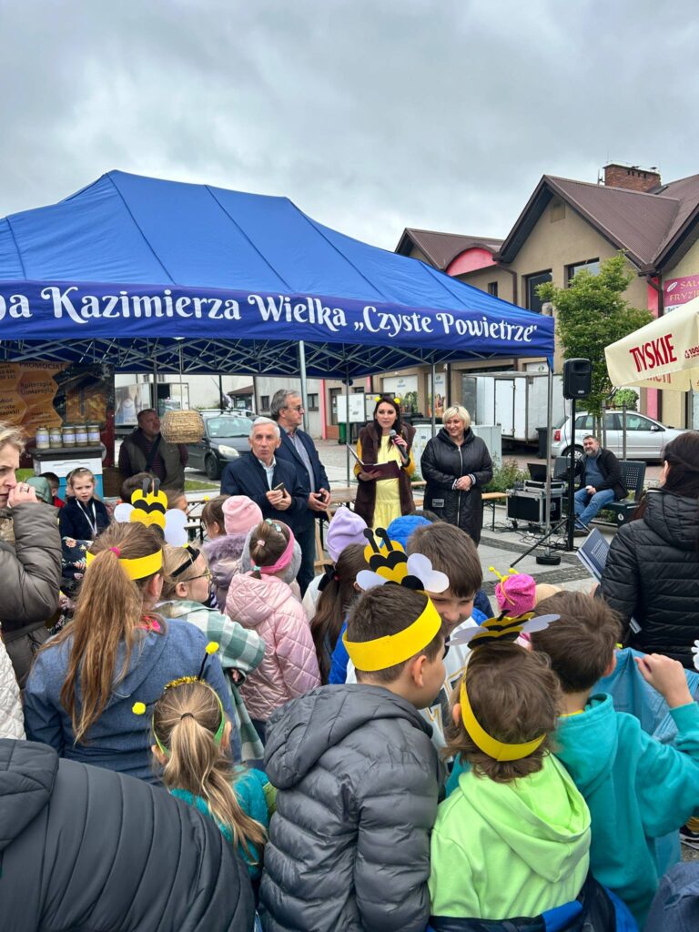 Namiot "Gmin Kazimierza Wielka - Czyste Powietrze". Przy namiocie znajduje się burmistrz wraz z innymi osobami, w tym m.in. pszczelarzem i dziećmi z lokalnych szkół