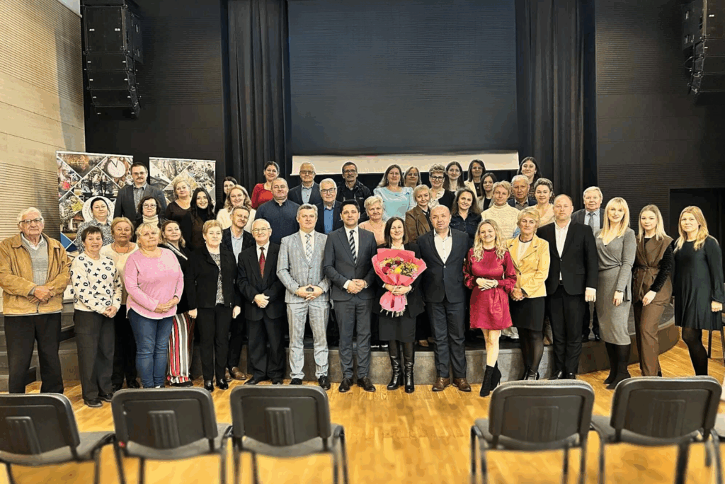 Członkowie LGD "E.O.CENOMA" wraz z członkami zarządu oraz członkami komisji rewizyjnej i pracownikami biura ustawieni wszyscy razem do zdjęcia. Na zdjęciu znajdują się także Wójtowie oraz Burmistrzowie gmin członkowskich LGD. Na środku Pani prezes wraz z wręczonymi jej kwiatami za jej dotychczasową funkcję na stanowisku Prezesa Zarządu. 