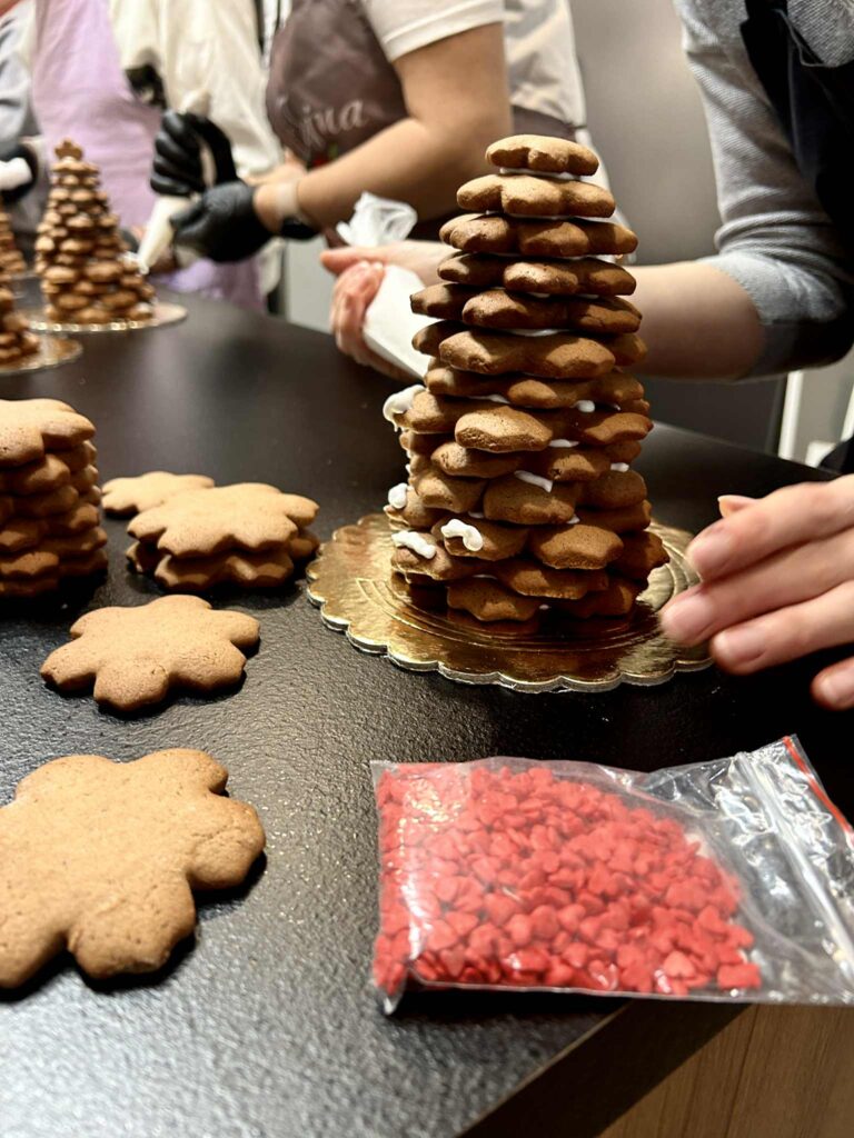 Składanie przez jedną z uczestniczek choinki bożonarodzeniowej z pierników