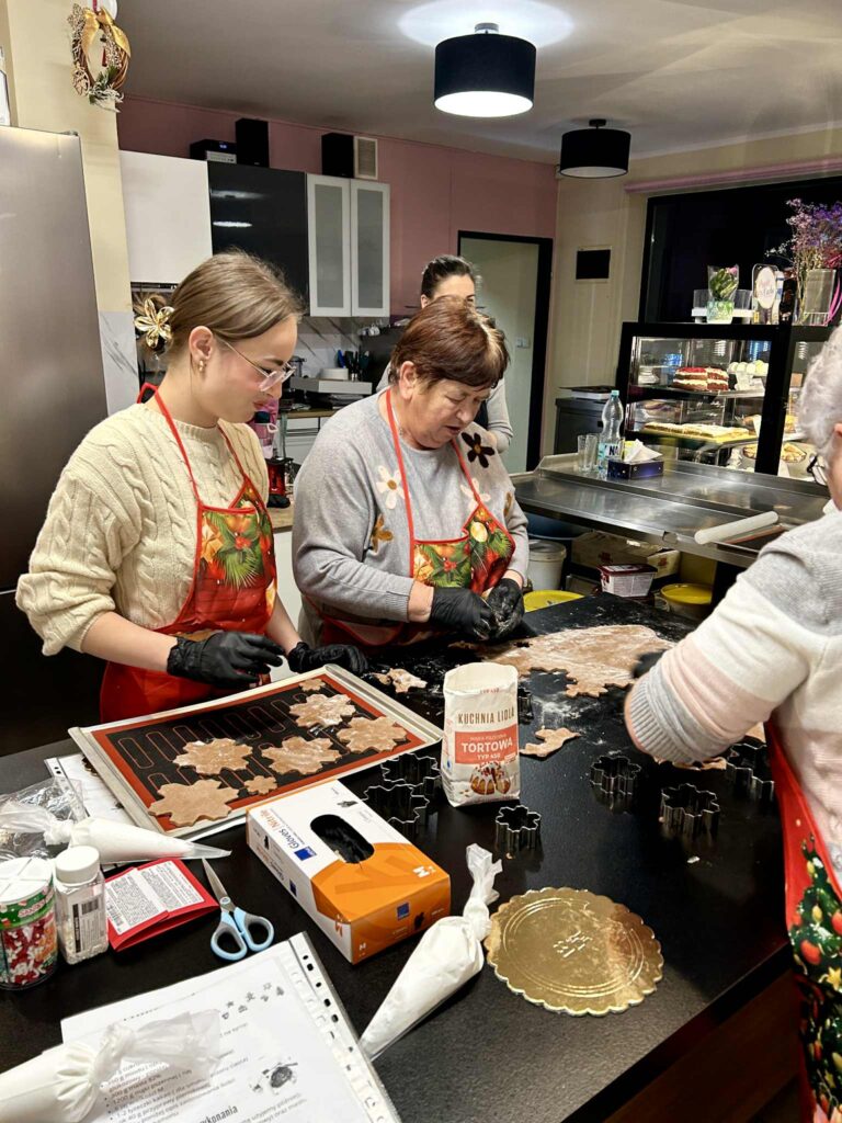 Zdjęcie przedstawiajace uczestniczki układające wycięte pierniki na blachę do pieczenia