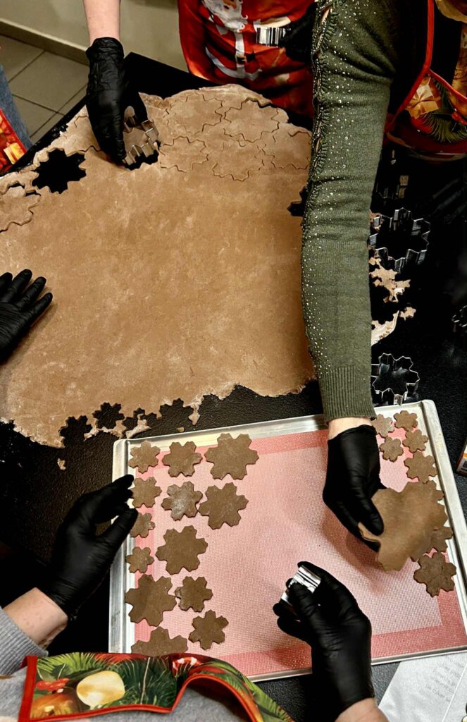 Zdjęcie przedstawiające ręce wycinające foremkami kształt pierników z ciasta