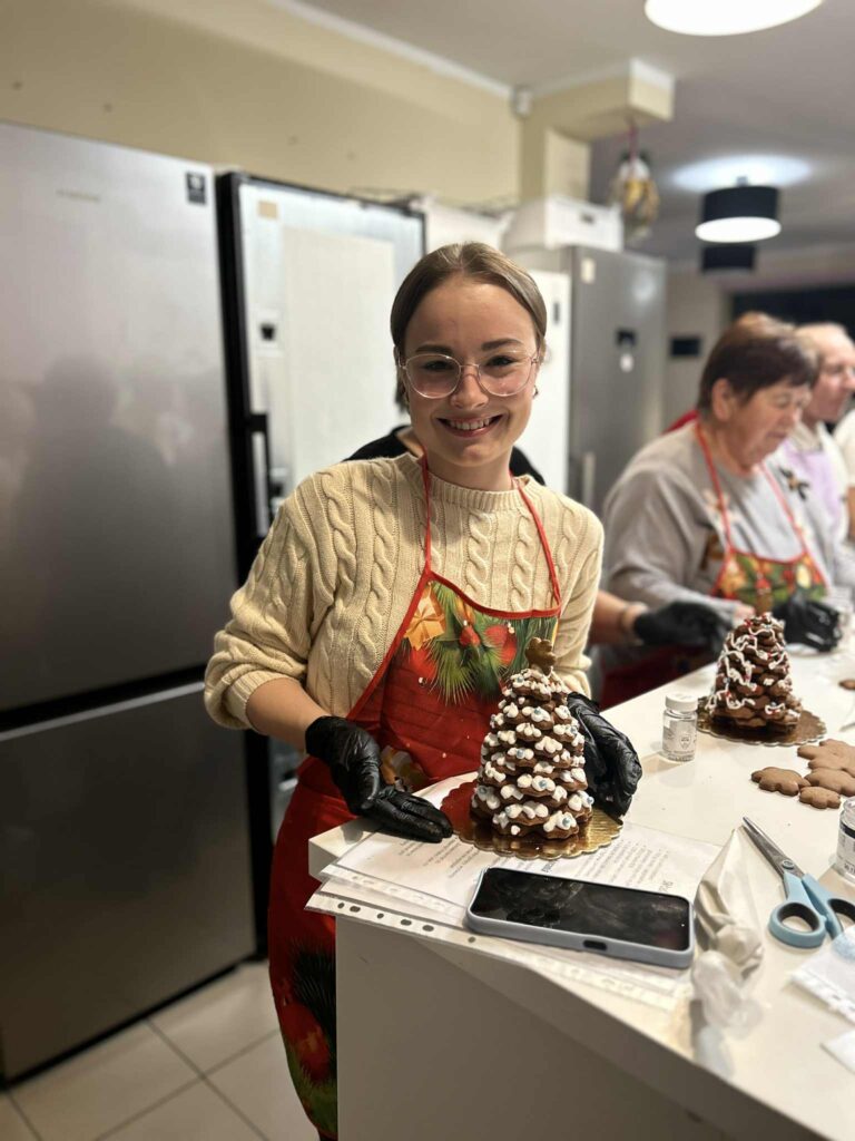 Uczestniczka warsztatów prezentujaca złożoną choinkę i udekorowaną lukrem