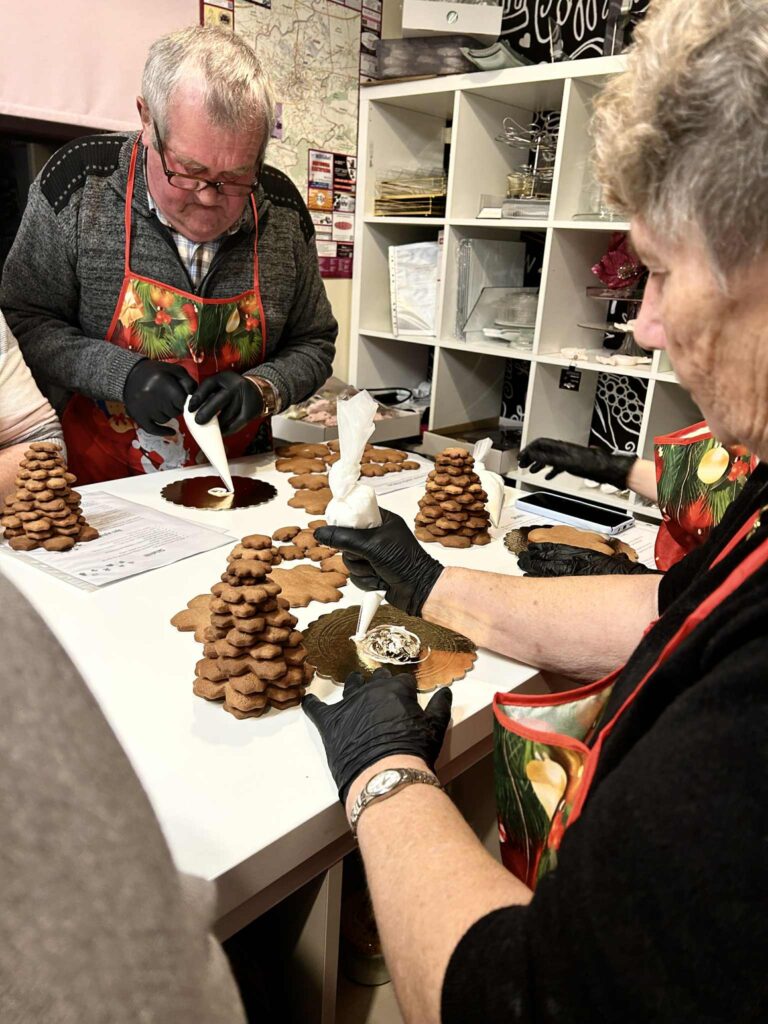 Pani i Pan dekorujący złożoną już choinkę bożonarodzeniową.